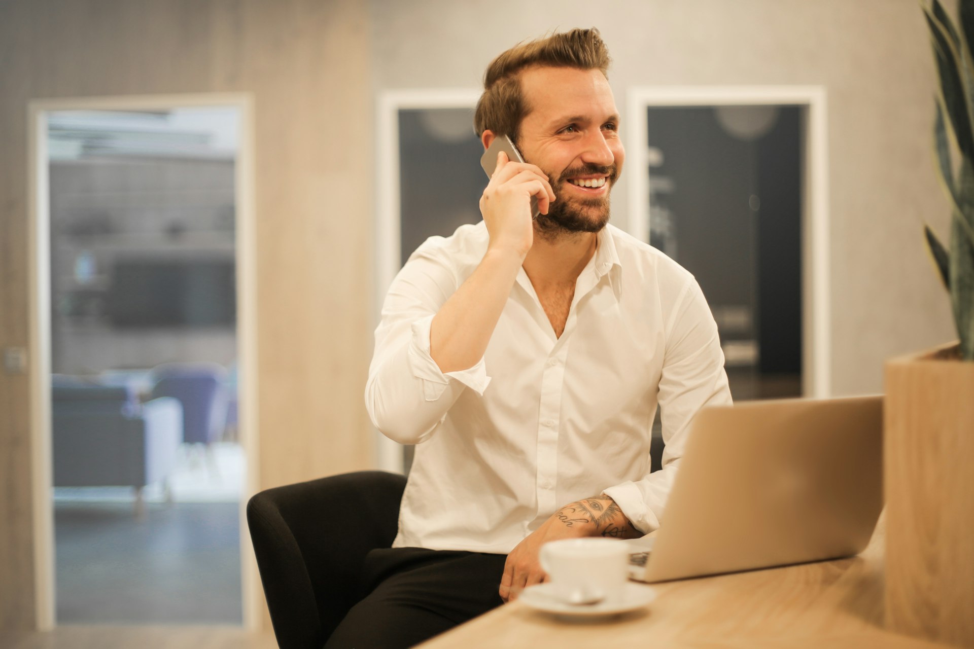 Smiling businessman on a phone call in a modern office, showing remote founders managing business in Poland