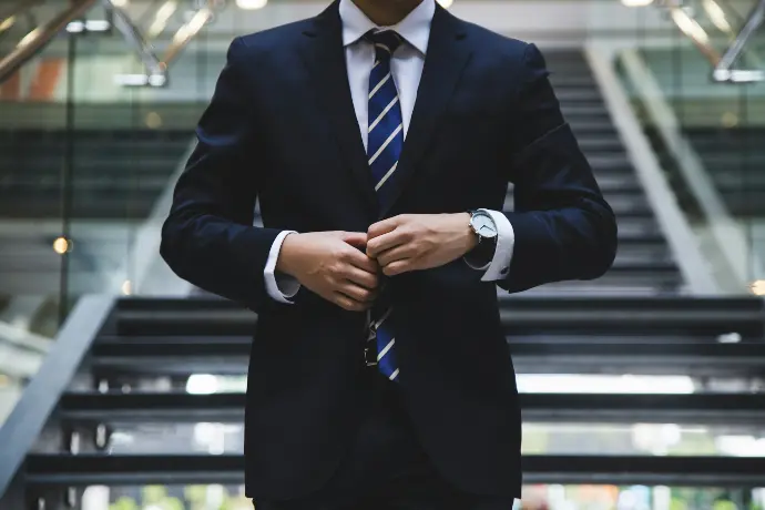 Businessman adjusting suit jacket while standing on office stairs