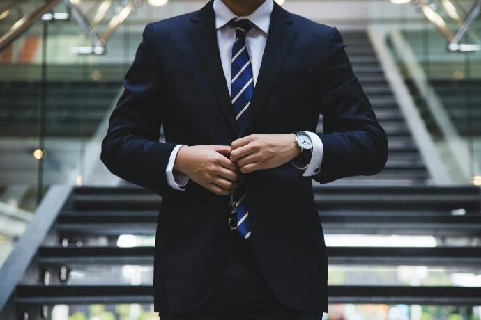 Businessman in a suit adjusting his tie in a modern office